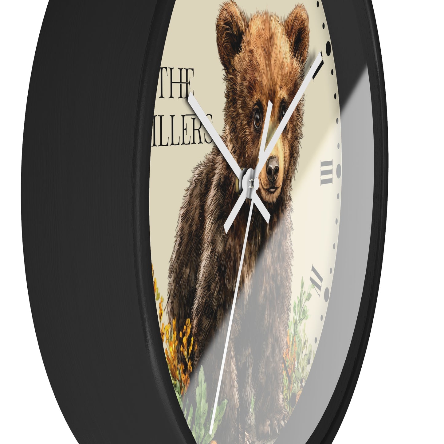 A round wall clock with a black frame and a printed face showing a brown bear illustration over a cream background, with black Roman numerals and white hands.
