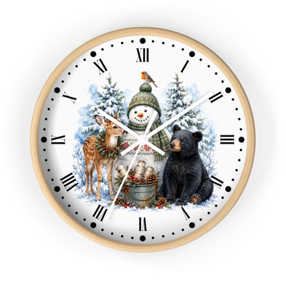 A round wall clock with a light wood frame and a white face featuring a winter holiday illustration. The design shows a snowman in a green hat and scarf, a black bear, a deer, evergreen trees, and a bird, with black Roman numerals and hands on a clean white background.