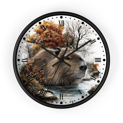 Round wall clock with a black frame and a printed nature scene featuring a capybara in shallow water with autumn trees and a misty forest background. Roman numerals and black dot hour markers replace standard clock markings.