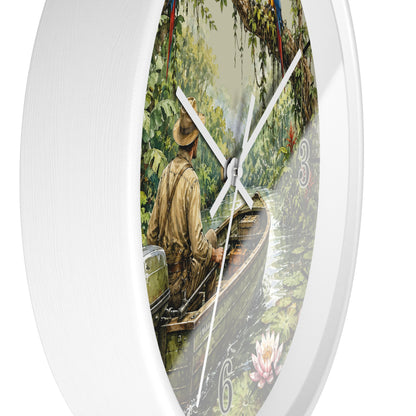 A round white wall clock featuring a printed illustration of a man in a boat on a river surrounded by lush green trees and water lilies. The clock has white hands and the number 6 visible on the lower right side.