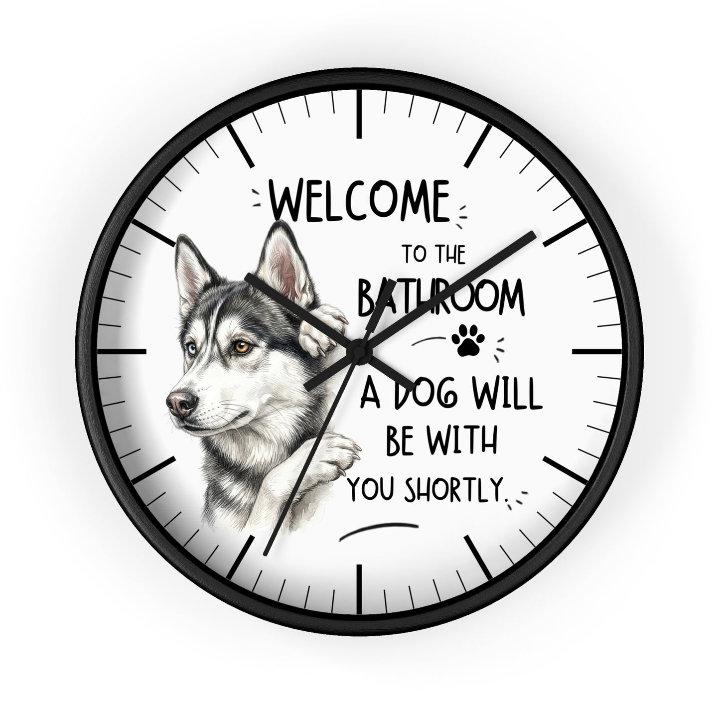 A round wall clock with a black frame and a white face, featuring a sketch of a husky dog and the text 'WELCOME TO THE BATHROOM A DOG WILL BE WITH YOU SHORTLY.' on a light gray background.