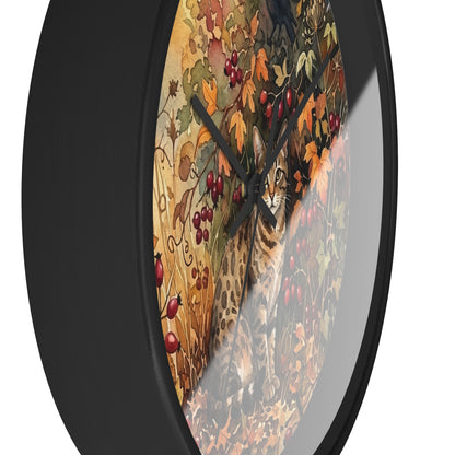Round wall clock with a black frame and a printed autumn scene featuring a spotted cat among leaves and red berries, shown on a white background.