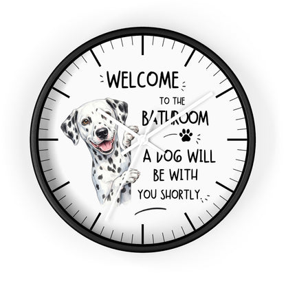 A round wall clock with a black frame and white face, featuring a Dalmatian illustration and the text 'WELCOME TO THE BATHROOM A DOG WILL BE WITH YOU SHORTLY'.