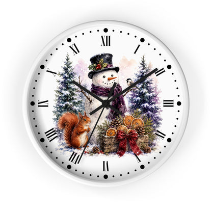 A round white wall clock with a festive winter illustration on the face, featuring a snowman in a top hat, a squirrel, evergreen trees, and gift baskets. The clock has black Roman numerals and black hands, shown against a plain white background.