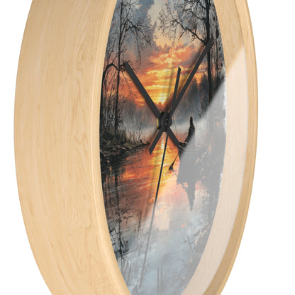 Oval wall clock with a light natural wood frame and a printed scenic print of a forest lake at sunset on the face, with black clock hands.