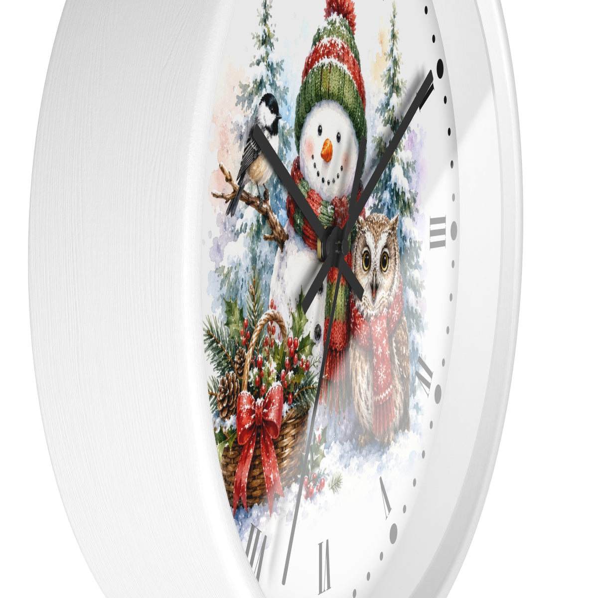 A round white wall clock with a festive winter illustration on the face, featuring a snowman in a red and green hat, a bird on a branch, an owl, evergreen trees, and a basket with red bows. The clock is shown against a plain white background.