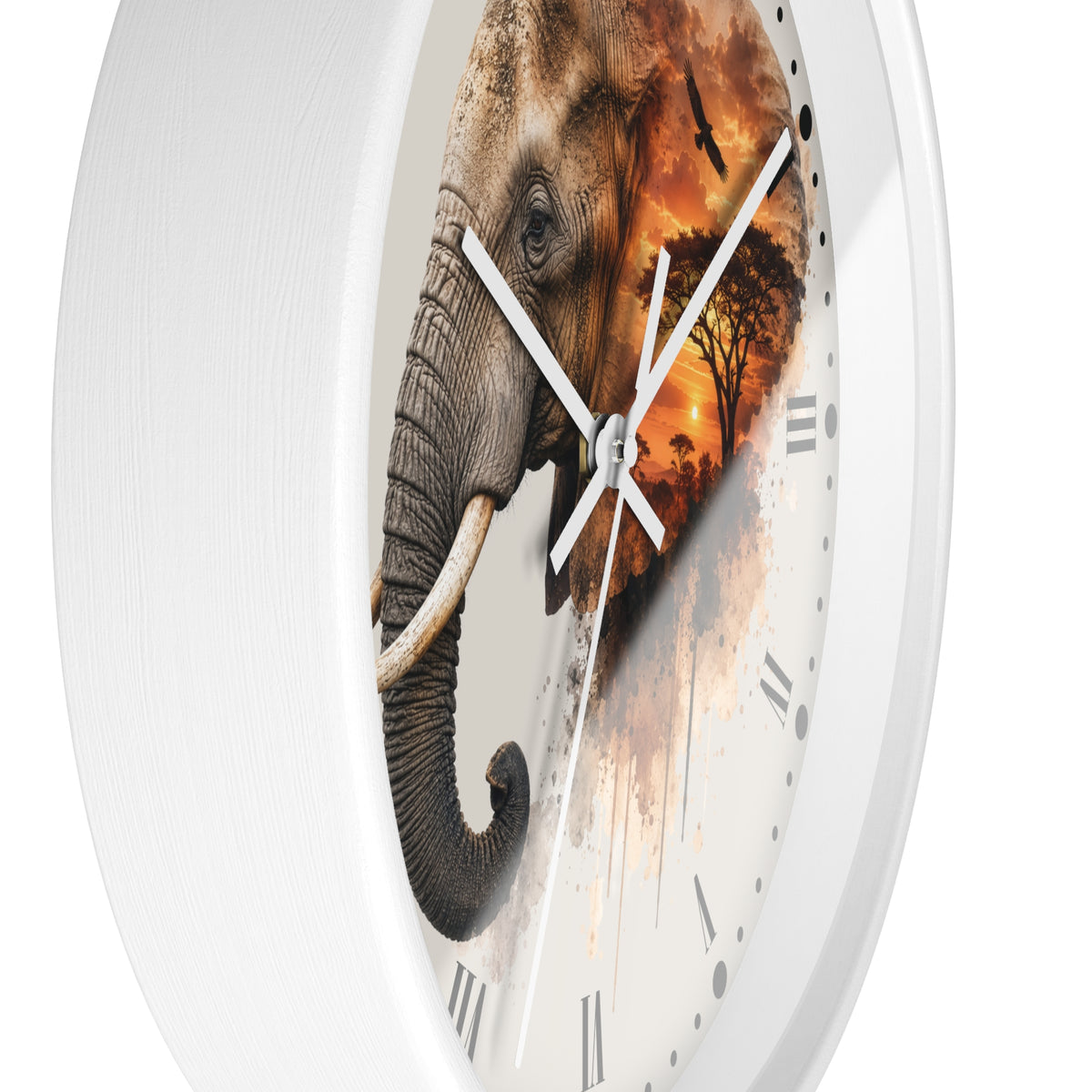 A round wall clock with a white frame and a printed elephant design on the face. The elephant blends into a warm sunset scene with orange and brown tones, and the clock has white hands and black Roman numerals.