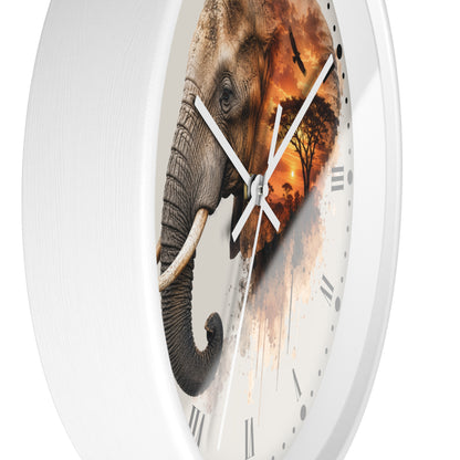 A round wall clock with a white frame and a printed elephant design on the face. The elephant blends into a warm sunset scene with orange and brown tones, and the clock has white hands and black Roman numerals.