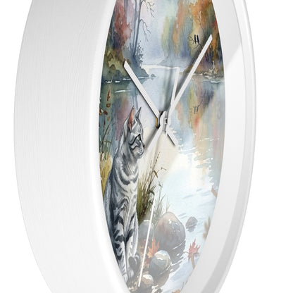 Round white wall clock featuring a printed illustration of a gray tabby cat sitting by a reflective water scene with autumn trees and rocks.