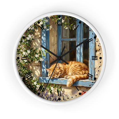 Round wall clock with a white frame and a printed illustration of a sleeping orange tabby cat resting on a blue window sill, surrounded by climbing white flowers and green leaves. The clock has black hands, black Roman numerals, and is shown against a plain white background.