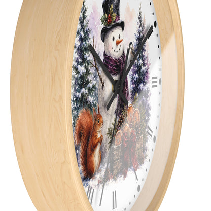 A round wall clock with a light natural wood frame and a white face featuring a winter scene with a snowman, snow squirrel, evergreen trees, and a rustic wooden sign.