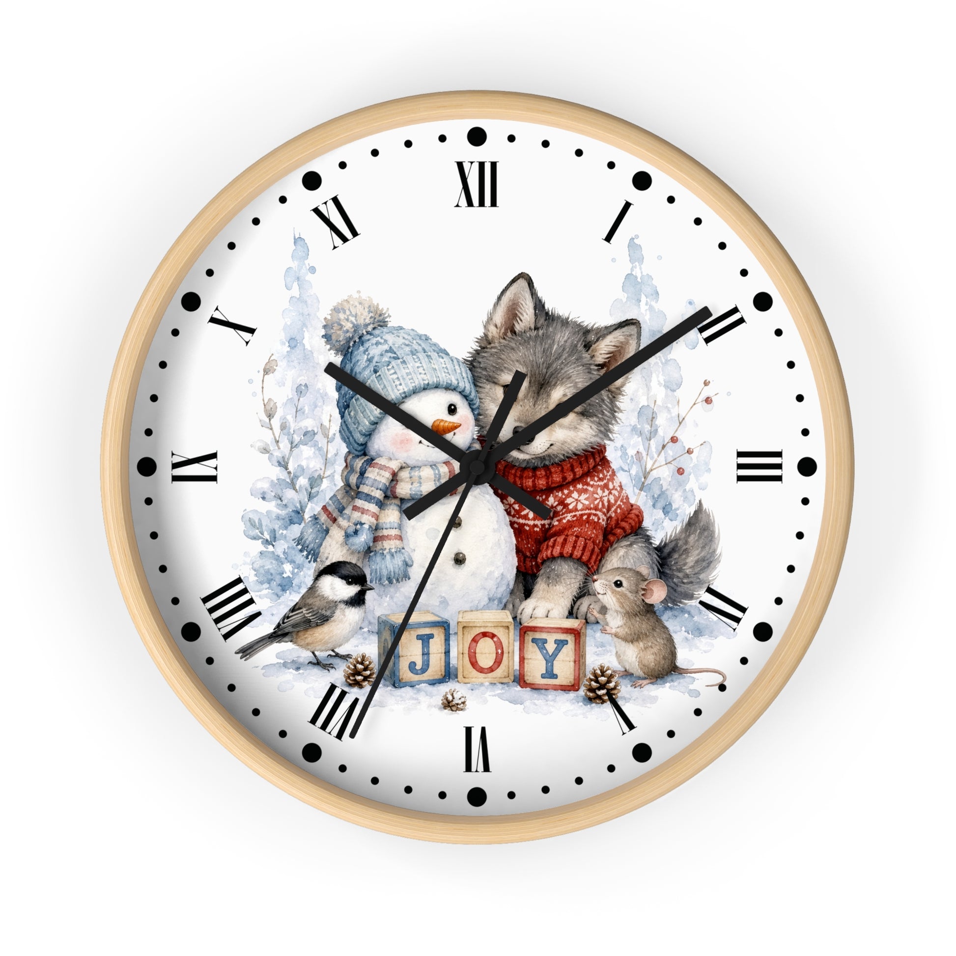 A round wall clock with a light natural wood frame and a white face, decorated with a winter holiday illustration featuring a wolf in a red sweater, a snowman in a blue hat, a small bird, a mouse, and the word 'JOY' spelled out by wooden blocks. The clock has black Roman numerals and hands and is shown against a plain white background.