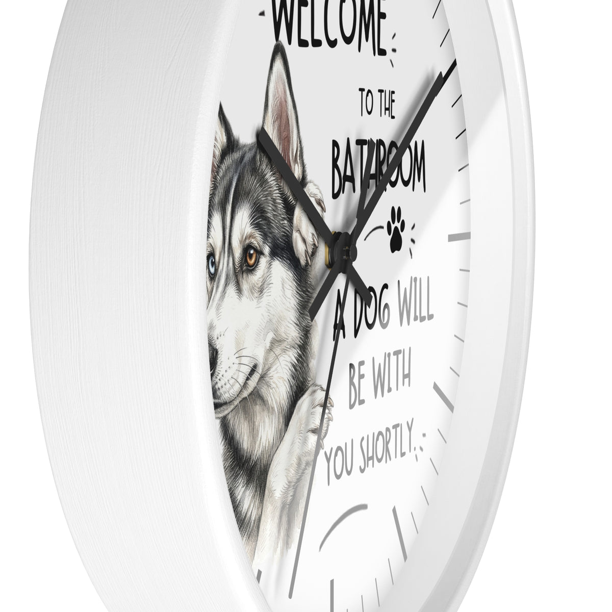 A white round wall clock with a husky dog illustration and the humorous text 'WELCOME TO THE BATHROOM A DOG WILL BE WITH YOU SHORTLY' printed on the face.