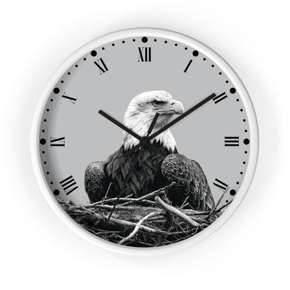A round wall clock with a white frame and a monochrome photograph of a bald eagle sitting in a nest on the clock face, with black Roman numerals and hands on a light gray background.