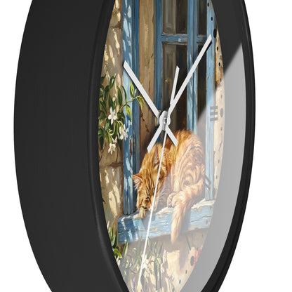Round wall clock with a black frame and a printed illustration of an orange tabby cat resting on a blue window sill, shown against a plain white background.