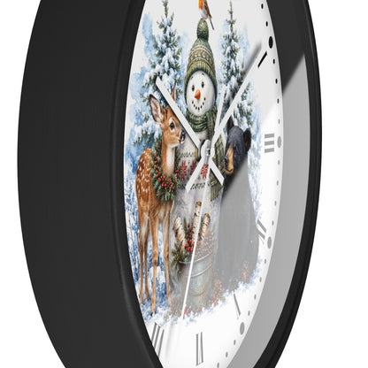 A round wall clock with a black frame and a white face featuring a winter holiday illustration of a snowman, deer, bear, and snowy trees.