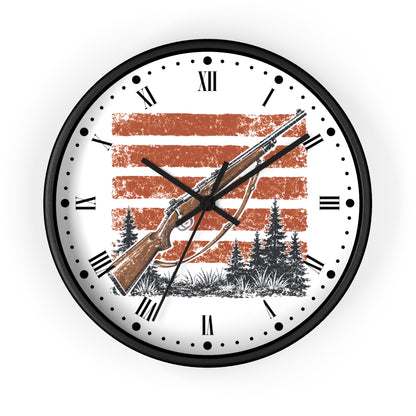 A round wall clock with a black frame and a white face featuring a hunting rifle design over a distressed orange and white striped background, with black Roman numerals and hands.