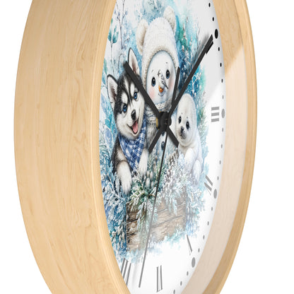 A round wall clock with a light natural wood frame and a printed winter illustration on the face, showing a husky, a snowman, and a puppy in snowy scenery. The clock is photographed against a plain white background.