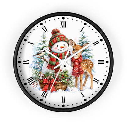 A round wall clock with a black frame and a white face featuring a festive Christmas illustration of a snowman, a deer, evergreen trees, and holiday decorations. The clock uses Roman numerals for hour markers and has black hands with silver tips.