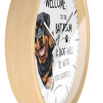 A round wall clock with a light natural wood frame and a white face. The clock face features a photo of a Rottweiler dog and the text 'WELCOME TO THE BATROOM A DOG WILL BE WITH YOU SHORTLY'.