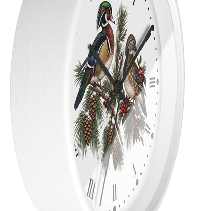 A white round wall clock with a detailed winter woodland illustration featuring two wood ducks perched on pine branches with pinecones and red berries.