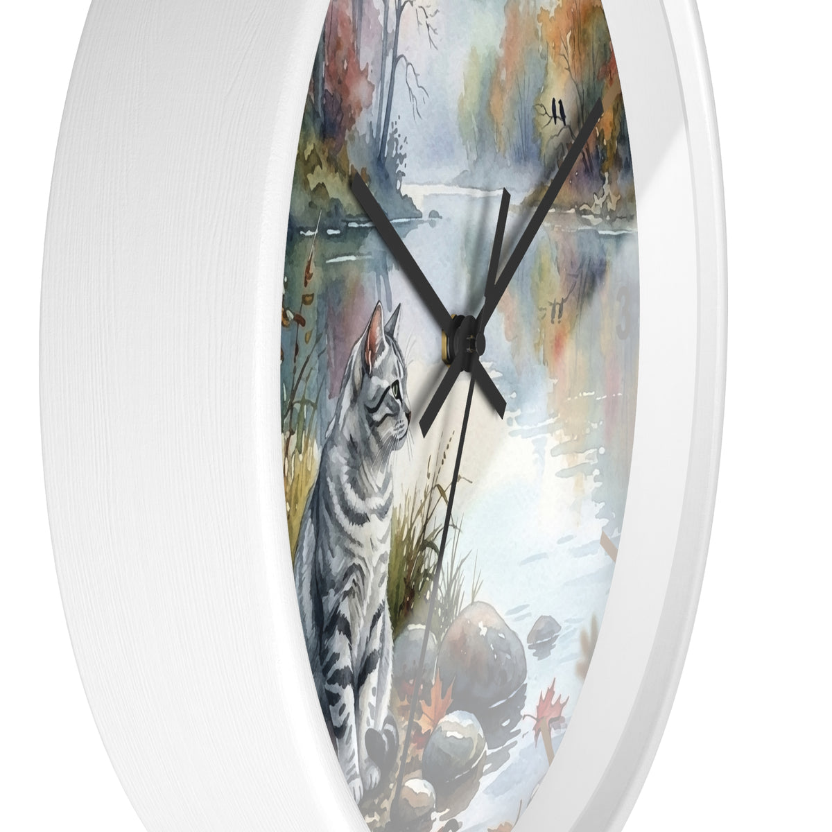 Round wall clock with a white frame and a printed watercolor-style illustration of a gray tabby cat beside a reflective pond, with black hands and no visible numbers.