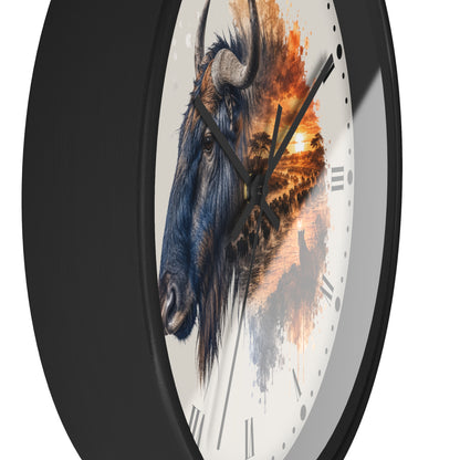 A close-up of a round wall clock with a black frame and a white dial featuring a painted bison head and an orange sunset landscape design.