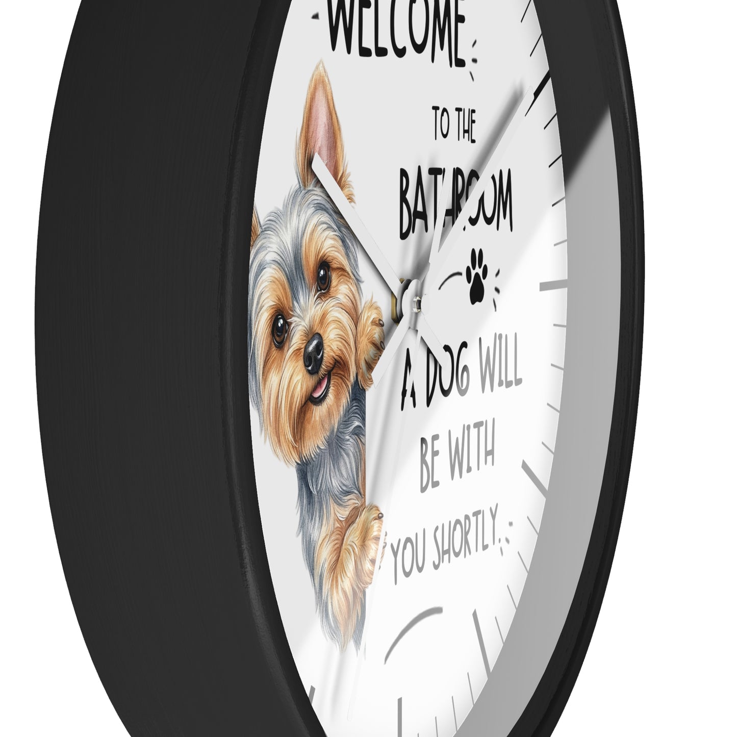A round wall clock with a black frame and a white face, featuring an illustration of a Yorkshire Terrier and the humorous text 'WELCOME TO THE BATHROOM A DOG WILL BE WITH YOU SHORTLY'.