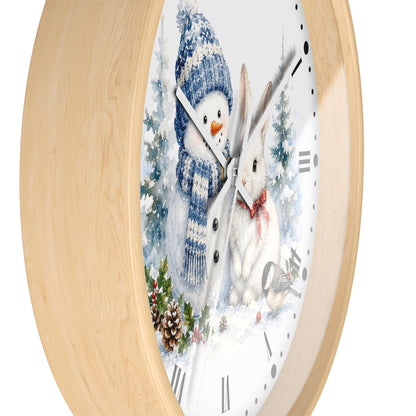 A round wall clock with a light natural wood frame and a white face featuring a winter illustration of a snowman in a blue hat and scarf next to a white rabbit with a red bow tie.