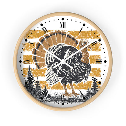 A round wall clock with a light natural wood frame, featuring a distressed design of a black and brown turkey over horizontal gold stripes on a white background, with black Roman numerals and clock hands.