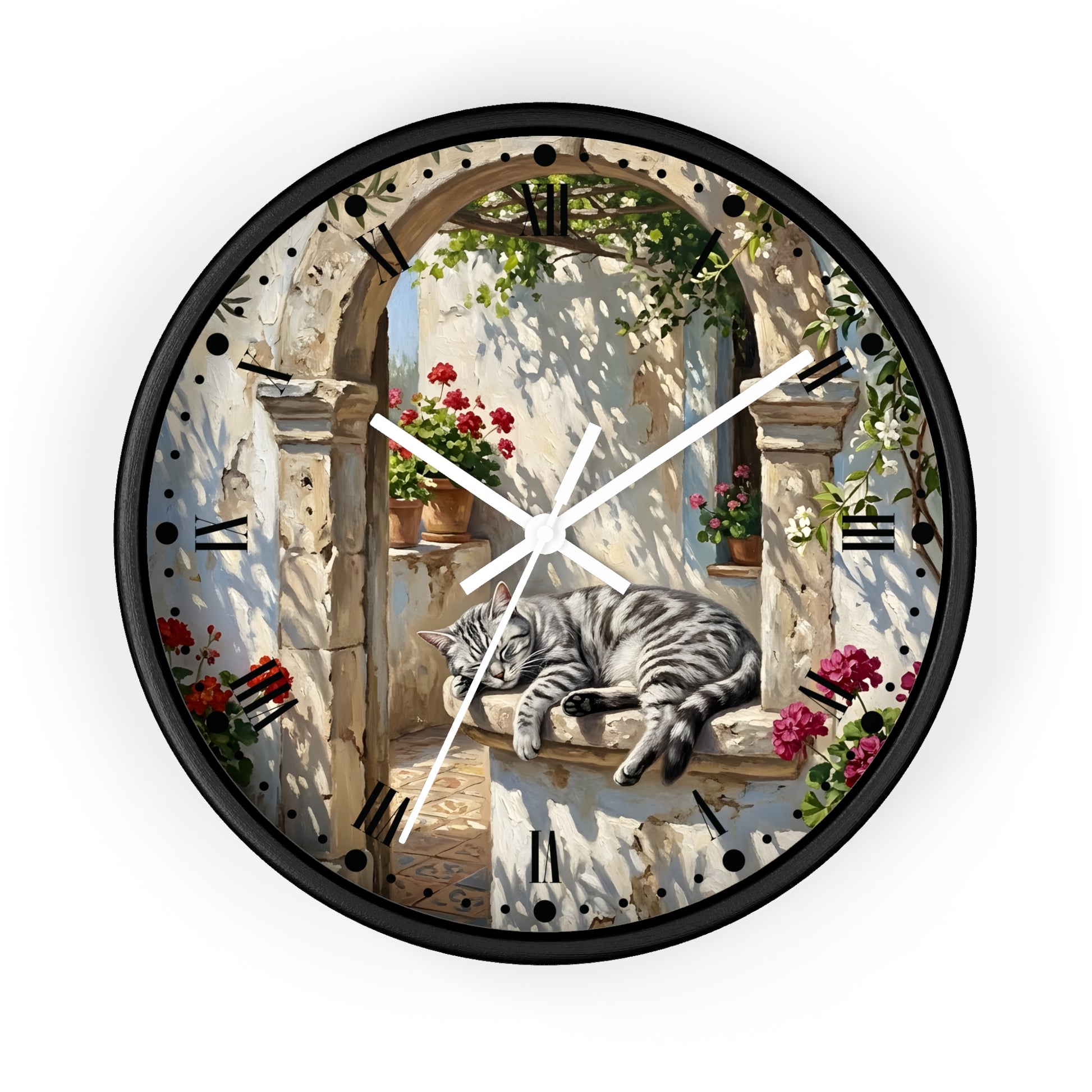 A round wall clock with a black frame and white hands, featuring a printed design of a gray tabby cat resting on a stone ledge in an outdoor archway scene with flowers and greenery.