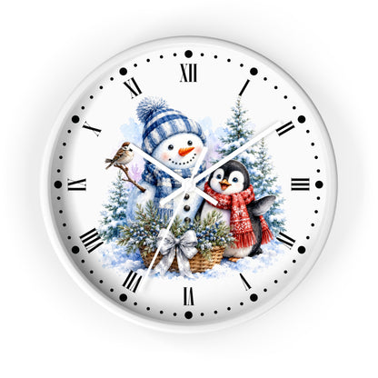 A round white wall clock with black Roman numerals and markers, featuring a winter illustration of a snowman in a blue striped hat and scarf, a penguin in a red scarf, evergreen trees, and a bird on the clock face.