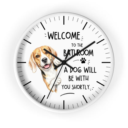 A round white wall clock with black hands and hour markers, featuring a beagle illustration and the text 'WELCOME TO THE BATHROOM A DOG WILL BE WITH YOU SHORTLY' on a white background.