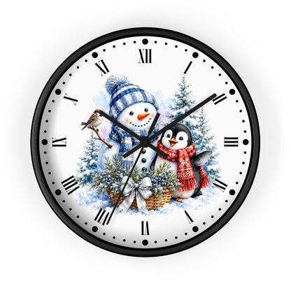 A round wall clock with a black frame and a white face featuring a winter holiday illustration of a snowman, a penguin, evergreen trees, and a bird, with black Roman numerals and hands.