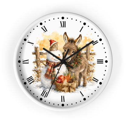 A round wall clock with a white face, black Roman numerals, and black hands, featuring a festive winter illustration of a snowman and a donkey with autumn elements in the background.