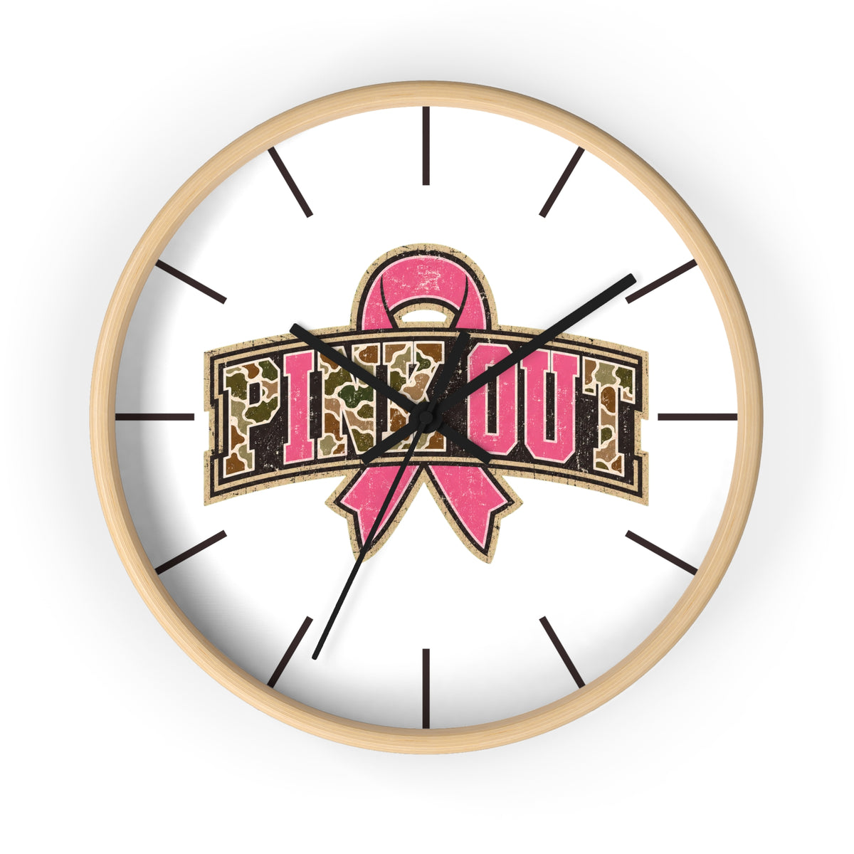 A round wall clock with a light wood frame and a white face, featuring a pink ribbon and the words 'PINK OUT' in a leopard-print style. The clock hands are black and the hour markers are minimalist black lines.