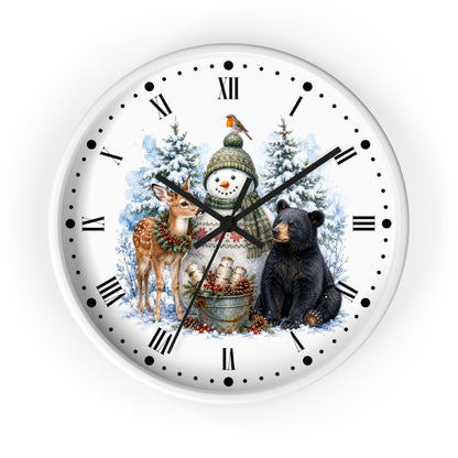 A round wall clock with a white face featuring a winter holiday illustration. The design shows a snowman in a green knit hat and scarf, a black bear, a deer, snow trees, and a small bird, with black Roman numerals and hands on a white background.