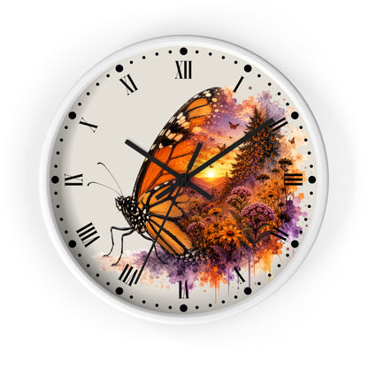 A round wall clock with a white frame and a printed dial featuring a large orange-and-black butterfly over a colorful sunset landscape with purple and orange watercolor splashes. The clock has black Roman numerals and black hands on a white background.