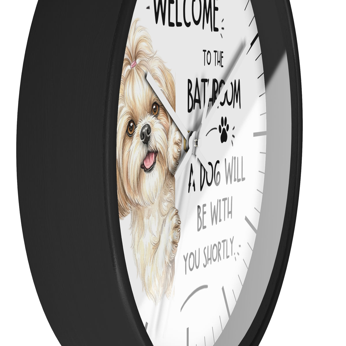 A round wall clock with a black frame and a white face featuring a watercolor illustration of a small fluffy dog and the text 'WELCOME TO THE BATHROOM A DOG WILL BE WITH YOU SHORTLY'.