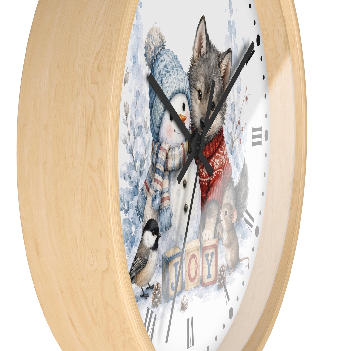 A round wall clock with a light natural wood frame and a whimsical winter illustration on the face. The artwork shows a penguin in a blue knit hat and scarf, a gray wolf in a red sweater, a small bird, a squirrel, and the word "JOY" in colorful blocks.