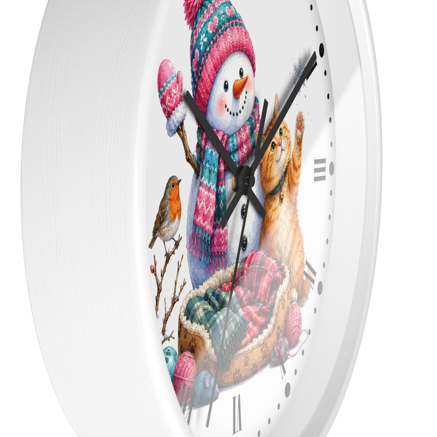 A white round wall clock with a festive winter illustration featuring a snowman in a pink knit hat and scarf, a ginger cat in a basket, a small bird, and yarn balls on the clock face.