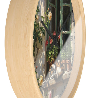 Round wall clock with a light natural wood frame and a printed scenic face showing a sunlit stone wall, green window, climbing flowers, and a cat on a windowsill.