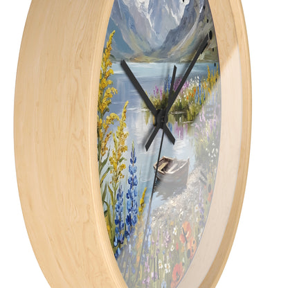 A roundl wall clock with a light natural wood frame and a scenic landscape print featuring a lake, mountains, wildflowers, and a small boat, shown against a plain white background.