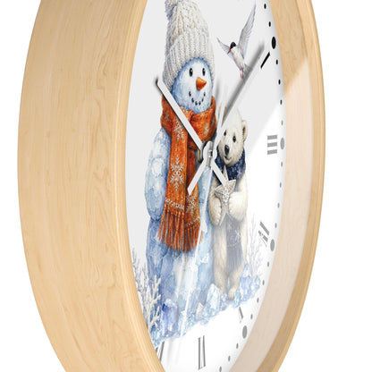A round wall clock with a light natural wood frame and a white face featuring a winter illustration of a snowman in a knit hat and scarf next to a teddy bear.