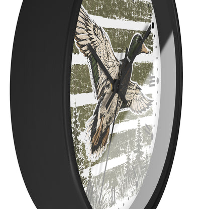 Round wall clock with a black frame and a printed dial featuring a flying mallard duck over a rustic white and olive green striped background.