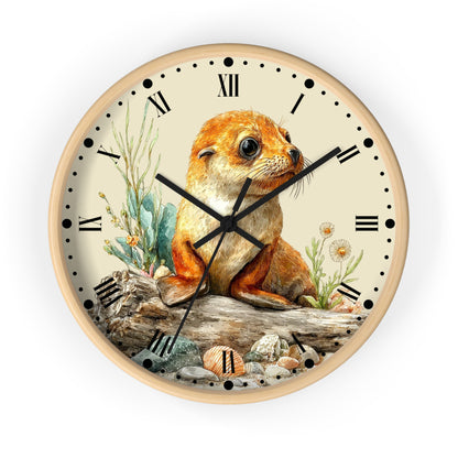 A round wall clock with a light wood frame and a cream-colored face, featuring a detailed illustration of a seal pup sitting on a log with rocks and plants. The clock has black Roman numerals and black hands.