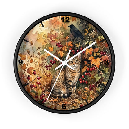 A round wall clock with a black frame and a detailed autumn-themed illustration on the face, featuring a tabby cat, a crow, berries, and fall leaves. The clock is shown against a plain white background.