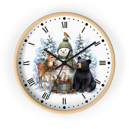 A round wall clock with a light wood frame and a white face featuring a winter holiday illustration of a snowman, deer, black bear, snow trees, and a bird, with black Roman numerals and hands on a white background.