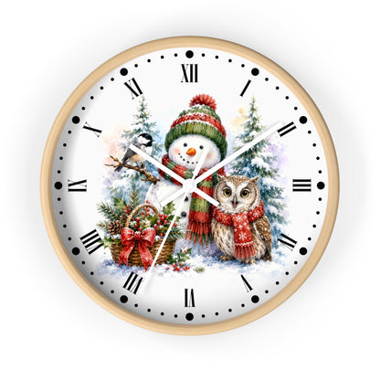 A round wall clock with a light wood frame and a white face featuring a festive Christmas illustration of a snowman and owl, Roman numerals, and black minute markers.