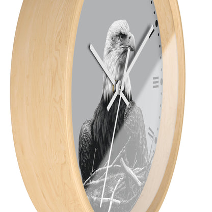 Oval wall clock with a light natural wood frame and a monochrome photograph of a bald eagle on the clock face, with white hands and Roman numeral markers.
